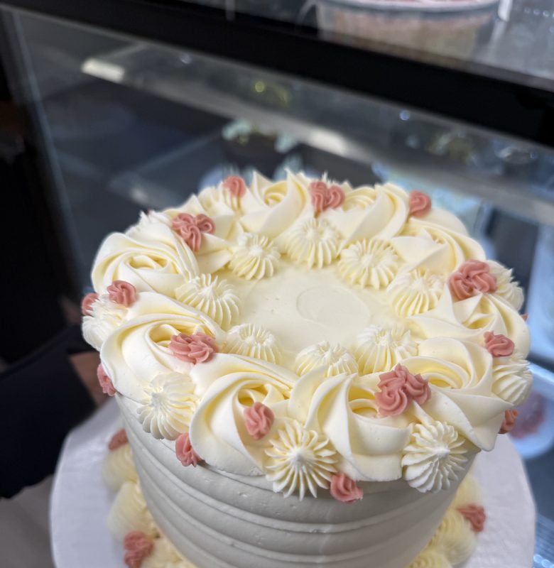A white buttercream cake with piped pink and white flowers