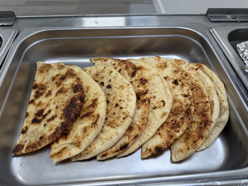 Griddled parathas fanned out in a steel tray